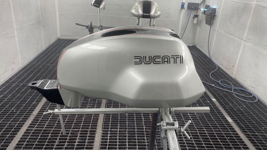Professionelle Design-Lackierung eines Ducati-Motorradtanks mit originalgetreuem Schriftzug durch Oberland Lackdoc, Ihre Autolackiererei in 83661 Lenggries.